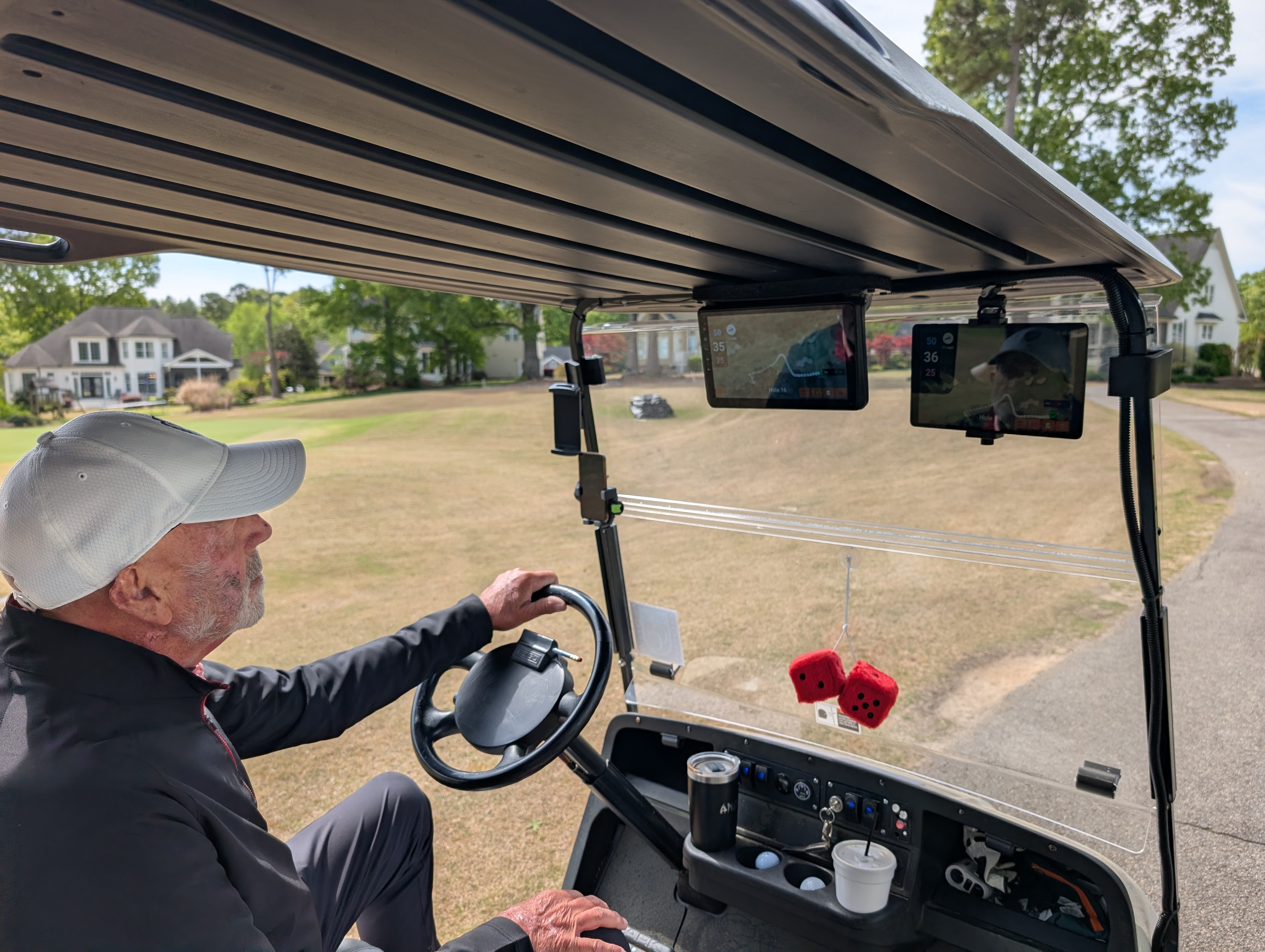 Golfer driving cart with two Aimy GPS screens showing distances ahead